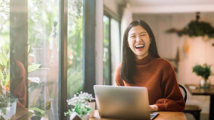 Happy young asian girl working at a coffee shop with a laptop