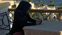 Mengenakan setelah hitam, ini pose Shobibah kala makan di restoran dengan pemandangan laut lepas. Foto: Instagram @obib_nahrawi