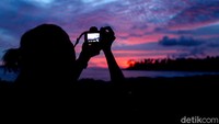 Salah seorang wisatawan mengabadikan keindahan momen matahari terbenam di Sinabang, Pulau Simeulue, Aceh.