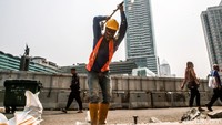 Sejumlah warga nampak melintas di area sekitar proyek pelebaran trotoar di kawasan Bundaran HI, Jakarta.