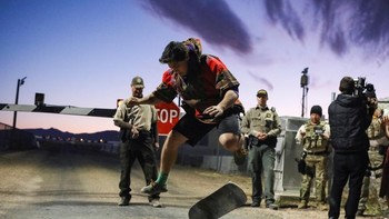 Seorang pemuda beraksi skate boar di hadapan aparat yang berjaga di depan area terlarang. Foto: Reuters