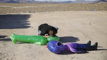 Seorang pria sibuk mempersiapkan aksesoris alien. Akan ada acara festival musik bertema alien di sana. Foto: AP