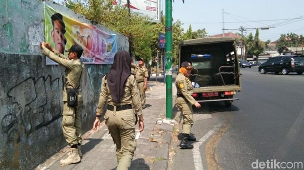 Petugas Satpol PP Surakarta mencopot spanduk Gibran Rakabuming Raka.