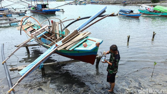 Dua orang nelayan memperbaiki kapalnya di Simeulue. Sebelumnya kapal tersebut telah digunakan untuk berburu lobster di tengah lauit.
