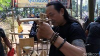 Seorang pengunjung menjajal mainan senapan yang terbuat dari bambu.