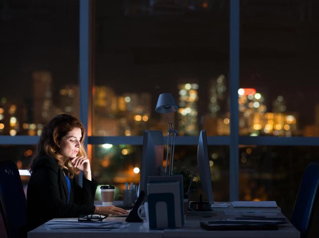 Pretty business woman working alone in dark office