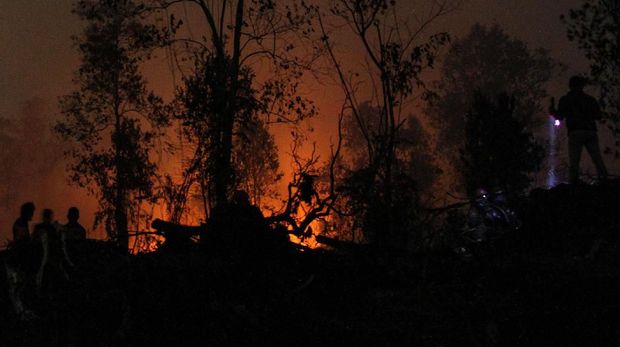 Satgas Karhutla Riau terus berjibaku memadamkan kebakaran lahan di Desa Rimbo Panjang, Kabupaten Kampar, Riau, Minggu (22/9/2019). Kebakaran lahan yang meluas dan mulai mengancam permukiman penduduk di kawasan tersebut membuat petugas terus melakukan upaya pemadaman hingga malam hari. ANTARA FOTO/Rony Muharrman/foc.