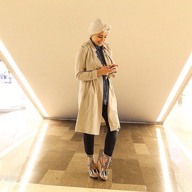 Wanita asal Kuwait ini kerap memadupadankan busana muslim dengan beraneka bentuk turban. Di foto ini, Ascia mengenakan kemeja denim yang dipadukan dengan coat ZARA panjang warna cokelat, dan hijab model turban berwarna nude, celana denim yang ia lipat dan wedges bertali yang cantik. Foto: Instagram @ascia