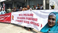 Saat demo, massa membawa spanduk berisi foto Mulan Jameela berjibab biru muda dan tulisan Dulu Pelakor Sekarang Perekor (Perebut Kursi Orang).