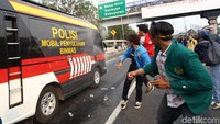 Beberapa mahasiswa melempari mobil polisi dengan botol air mineral.