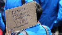 Seorang mahasiswa membawa tulisan Tuntaskan Reformasi Tuntaskan Skripsi saat melakukan aksi demo di depan gedung DPR.