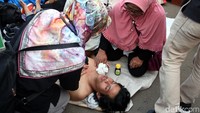 Seorang mahasiswa mendapat pertolongan dari para peserta aksi demo lainnya usai pingsan akibat kelelahan mengikuti demo di depan gedung DPR.
