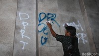 Petugas membersihkan coretan yang dibuat mahasiswa siang tadi.