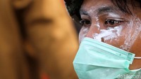 Seorang mahasiswa memakai odol di wajahnya untuk menghalau gas air mata.