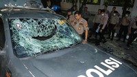 Tak hanya di Jakarta, Mobil Polisi di Medan turu menjadi sasaran mahasiswa. Polisi berada di samping mobil dinas yang rusak saat aksi unjuk rasa mahasiswa, di Gedung DPRD Sumut, di Medan, Sumatera Utara, Selasa (24/9/2019). Foto: ANTARA FOTO/Irsan Mulyadi