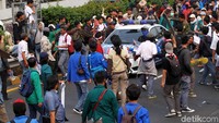 Sebuah mobil polisi melintas di tengah-tengah kerumunan massa yang memblokir tol.