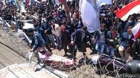 Massa menerobos kawat berduri yang dipasang aparat kepolisian.