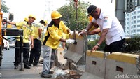 Satu per satu pembatas busway yang rusak diperbaiki oleh petugas.