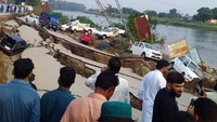 Keretakan jalan yang rusak parah membuat mobil-mobil berserakan.