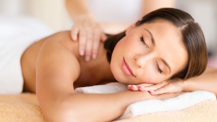 health, beauty, resort and relaxation concept - beautiful woman with closed eyes in spa salon getting massage