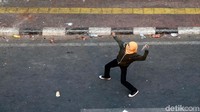 Seorang pelajar beraksi melempar batu ke arah gedung DPR.