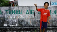 Seorang bocah Miangas memeprlihatkan cumi hasil tangkapannya di depan kamera usai berburu di pantai.