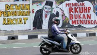 Seorang pengendara melintasi Jalan Pemuda di kawasan Rawamangun, Jakarta. Di salah satu dinding jalan nampak mural bertuliskan menolak RKUHP bukan menunda.