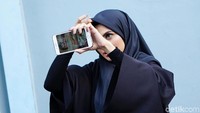 Asha tampak mengecek hijab dan rambutnya sebelum berpose di depan kamera. Pool/Palevi S/detikFoto.