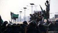 Dengan dilengkapi mobil komando dan sejumlah bendera, mereka menggelar orasi di jalan yang sudah dibarikade aparat kepolisian.