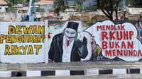 Nampak gambar Joker yang tengah memegang kartu berada di sebelah tulisan Menolak RKUHP Bukan Menunda.