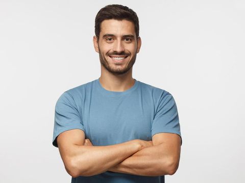 ilustrasi cara melipat tangan Portrait of smiling handsome man in blue t-shirt standing with crossed arms isolated on grey background