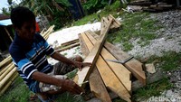 Seorang tukang kayu tengah menyelesaikan pekerjaannya.