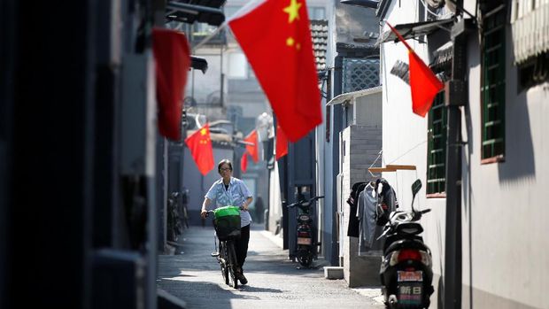 A resident cycles along a traditional alleyway, or hutong, with Chinese national flags to mark the 70th founding anniversary of People's Republic of China on October 1, in Beijing, China September 26, 2019. REUTERS/Jason Lee