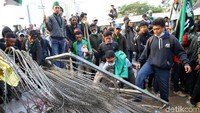 Mereka juga menginjak-injak kawat berduri yang dipasang polisi.