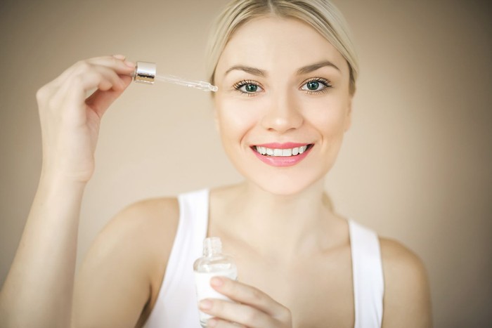 Woman with elegant makeup applying serum treatment. Space for copy.