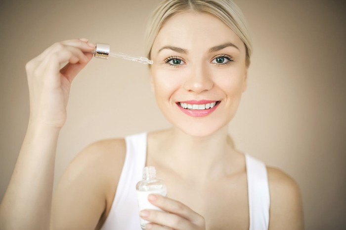 Skincare serum wajah Woman with elegant makeup applying serum treatment. Space for copy.