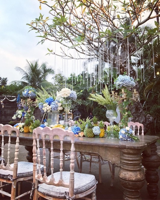 Selain Putri Marino, selebriti lainnya yang juga mengusung garden party untuk resepsi pernikahan mereka adalah Tyas Mirasih. Sentuhan biru terlihat diterapkan dalam dekorasi pernikahan Tyas dan Raiden Soedjono. Meja makan ditata cantik dengan hiasan buah dan bunga bernuansa biru. Ditambah hiasan lampu gantung yang menambah suasana semakin romantis saat senja tiba. Foto: Instagram