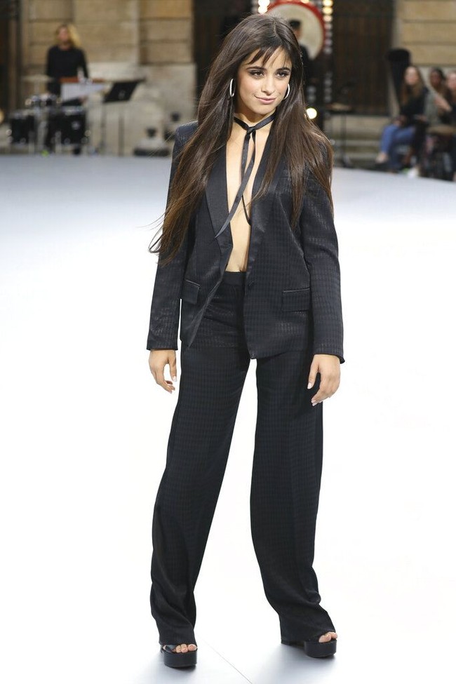 Camila Cabello tampil dengan power suit alias setelah blazer dan celana serba hitam di momen pertamanya sebagai model catwalk. Camila terlihat seksi karena dia tidak mengenakan apapun di balik blazernya. Foto: Vianney Le Caer/Invision/AP
