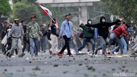 Massa aksi di belakang gedung DPR, Jakarta, nampak melemparkan batu ke arah polisi yang bersiaga di area sekitar tersebut.