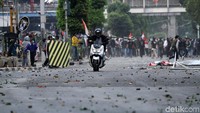 Seorang pengendara sepeda motor menggeber motornya agar terhindar dari lemparan batu.