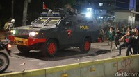 Massa melempar batu ke arah kendaraan taktis.