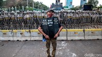 Seorang pendemo memamerkan poster di depan barikade kepolisian.