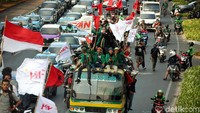 Beberapa duduk di atas bus sambil membawa sejumlah atribut.