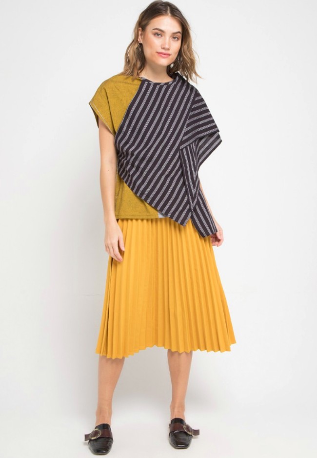 Untuk kondangan, Anda tak selalu harus mengenakan kebaya atau pakaian berbordir. Atasan berbahan batik pun dapat diandalkan. Tinggal sesuaikan saja bawahannya yang lebih maksimal. Anda bisa melirik Ero Lurik Top dari Isvara Batik seharga Rp 311 ribuan bermotif lurik ini. Anda bisa memadukannya dengan rok plisket bernuansa kuning seperti gambar. Foto: Zalora