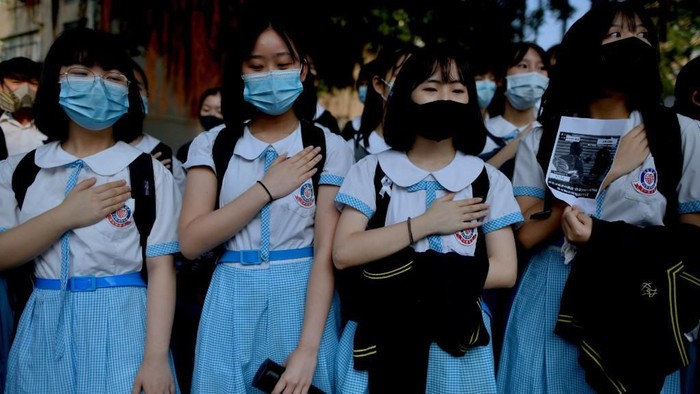 Schoolmates of form five student Tsang Chi-kin, 18, who was shot in the chest by police during violent pro-democracy protests that coincided with Chinas October 1 National Day, place their hands on their chests during a protest at a school in Hong Kong on October 2, 2019. - Hundreds of Hong Kongers staged a sit-in on October 2 outside the school of a protester who was shot by police as authorities said the wounded 18-year-old was now in a stable condition. (Photo by Mohd RASFAN / AFP)