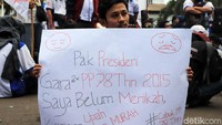 Seorang peserta aksi unjuk rasa membawa poster berisi curahan hatinya karena upah murah.