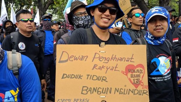 Massa buruh membawa poster yang nyeleneh.