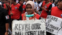 Seorang peserta aksi membawa poster yang berisi kritik dan menolak revisi UU Ketenagakerjaan no 13/2003.