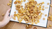 Baca buku sambil ngemil snack memang paling enak. Tapi nggak begini juga ya ngemilnya. Brand Chex Mix menuangkan sereal yang dituang pada buku sebagai salah satu media iklan. Foto: istimewa