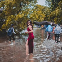 Warga lain yang berusaha menerjang banjir dijadikan sebagai latar belakang foto. Sementara wanita tersebut berpose dengan wajah tersenyum. Foto: Instagram/@meowwala